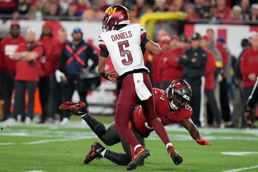 Washington Commanders quarterback Jayden Daniels (5) is pressured by Tampa Bay Buccaneers defensive tackle Calijah Kancey during the first half of an NFL wild-card playoff football game in Tampa, Fla., Sunday, Jan. 12, 2025. (AP Photo/Chris O'Meara)