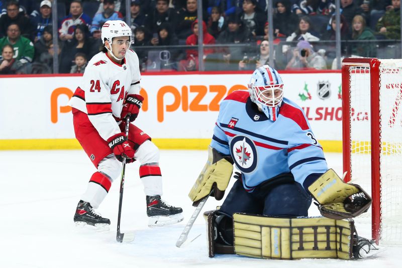 Dec 4, 2023; Winnipeg, Manitoba, CAN; Winnipeg Jets goalie Laurent Boissoit (39) makes a save as Carolina Hurricanes forward Seth Jarvis (24) looks for a rebound during the first period at Canada Life Centre. Mandatory Credit: Terrence Lee-USA TODAY Sports