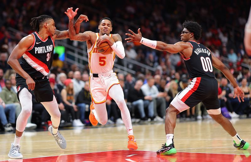 ATLANTA, GEORGIA - MARCH 27:  Dejounte Murray #5 of the Atlanta Hawks drives between Jabari Walker #34 and Scoot Henderson #00 of the Portland Trail Blazers during the fourth quarter at State Farm Arena on March 27, 2024 in Atlanta, Georgia.  NOTE TO USER: User expressly acknowledges and agrees that, by downloading and/or using this photograph, user is consenting to the terms and conditions of the Getty Images License Agreement.  (Photo by Kevin C. Cox/Getty Images)