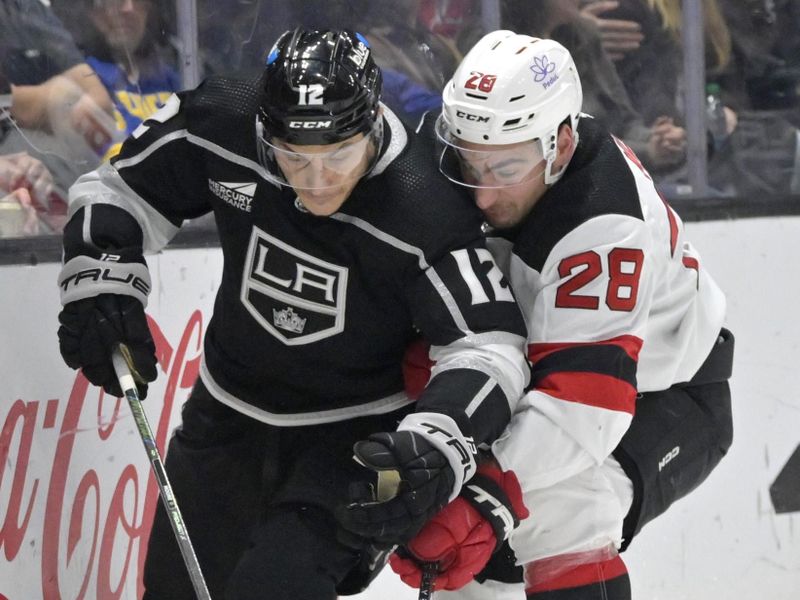 Mar 3, 2024; Los Angeles, California, USA; Los Angeles Kings left wing Trevor Moore (12) and New Jersey Devils right wing Timo Meier (28) battle along the boards in the second period at Crypto.com Arena. Mandatory Credit: Jayne Kamin-Oncea-USA TODAY Sports