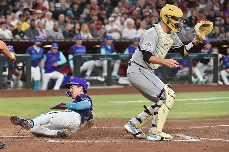 May 16, 2025; Phoenix, Arizona, USA;  Arizona Diamondbacks outfielder Corbin Carroll (7) slides to score as Colorado Rockies catcher Jacob Stallings (25) defends in the third inning at Chase Field. Mandatory Credit: Matt Kartozian-Imagn Images