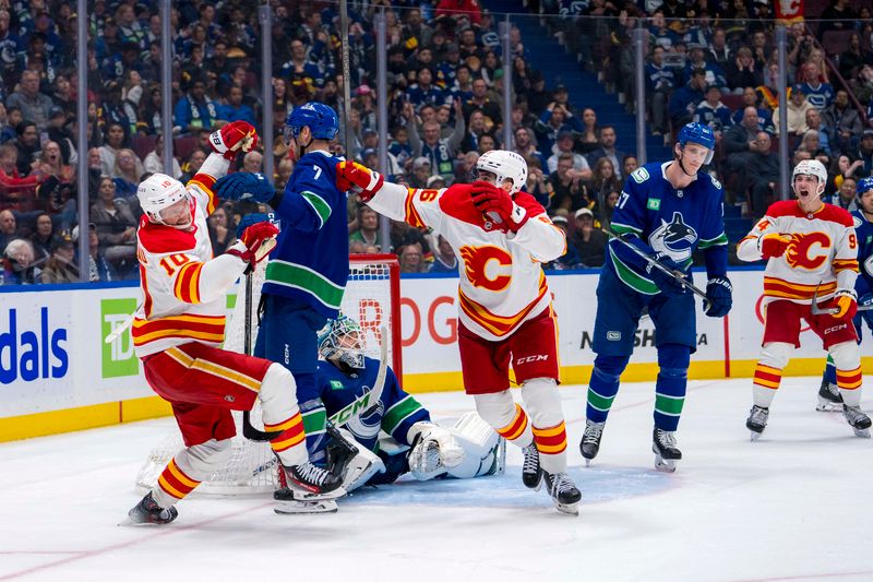 Oct 9, 2024; Vancouver, British Columbia, CAN; Vancouver Canucks goalie Arturs Silovs (31) and defenseman Carson Soucy (7) and defenseman Tyler Myers (57) watch as Calgary Flames forward Martin Pospisil (76) and forward Jonathan Huberdeau (10) celebrate Huberdeau’s goal during the third period at Rogers Arena. Mandatory Credit: Bob Frid-Imagn Images