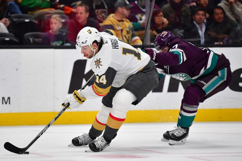 Dec 27, 2023; Anaheim, California, USA; Vegas Golden Knights defenseman Nicolas Hague (14) moves the puck ahead of Anaheim Ducks right wing Frank Vatrano (77) during the second period at Honda Center. Mandatory Credit: Gary A. Vasquez-USA TODAY Sports