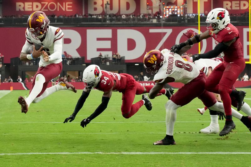 Washington Commanders quarterback Jayden Daniels, left, leaps into the end zone for a touchdown as Arizona Cardinals safety Jalen Thompson (34) defends during the second half of an NFL football game, Sunday, Sept. 29, 2024, in Glendale, Ariz. (AP Photo/Rick Scuteri)