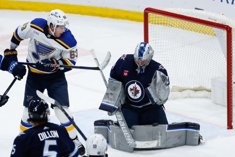 Feb 27, 2024; Winnipeg, Manitoba, CAN; Winnipeg Jets goalie Laurent Boissoit (39) makes a save as St. Louis Blues forward Jake Neighbours (63) looks for a rebound during the third period at Canada Life Centre. Mandatory Credit: Terrence Lee-USA TODAY Sports