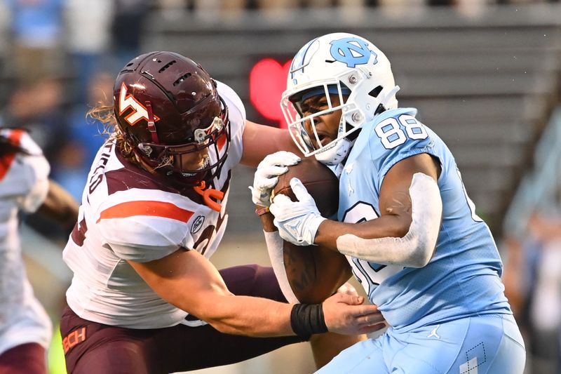 Oct 1, 2022; Chapel Hill, North Carolina, USA; North Carolina Tar Heels tight end Kamari Morales (88) catches a pass as Virginia Tech Hokies linebacker Dax Hollifield (25) defends in the fourth quarter at Kenan Memorial Stadium. Mandatory Credit: Bob Donnan-USA TODAY Sports