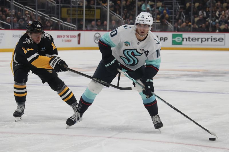 Jan 14, 2025; Pittsburgh, Pennsylvania, USA;  Seattle Kraken center Matty Beniers (10) skates with the puck against Pittsburgh Penguins center Cody Glass (19) during the second period at PPG Paints Arena. Mandatory Credit: Charles LeClaire-Imagn Images