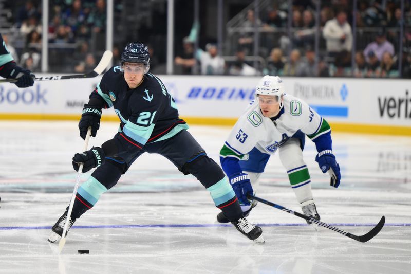 Feb 22, 2024; Seattle, Washington, USA; Seattle Kraken center Alex Wennberg (21) plays the puck while defended by Vancouver Canucks center Teddy Blueger (53) during the second period at Climate Pledge Arena. Mandatory Credit: Steven Bisig-USA TODAY Sports