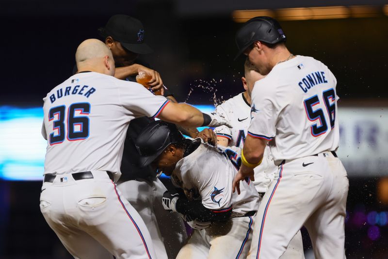 Sep 4, 2024; Miami, Florida, USA; Miami Marlins shortstop Xavier Edwards (center) celebrates with first baseman Jake Burger (left) and right fielder Griffin Conine (right) after hitting a walk-off single against the Washington Nationals during the tenth inning at loanDepot Park. Mandatory Credit: Sam Navarro-Imagn Images