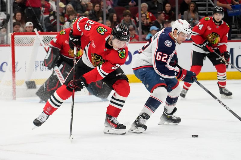 Dec 1, 2024; Chicago, Illinois, USA; Columbus Blue Jackets right wing Kevin Labanc (62) and Chicago Blackhawks center Philipp Kurashev (23) go for the puck during the second period at United Center. Mandatory Credit: David Banks-Imagn Images