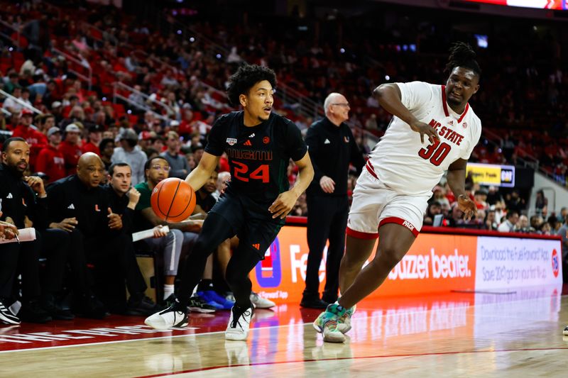 Jan 30, 2024; Raleigh, North Carolina, USA; Miami (Fl) Hurricanes guard Nijel Pack (24) dribbles with the ball guarded by North Carolina State Wolfpack forward DJ Burns Jr. (30) during the second half at PNC Arena. Mandatory Credit: Jaylynn Nash-USA TODAY Sports