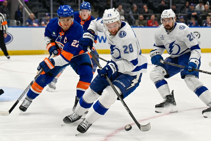 Dec 13, 2025; Elmont, New York, USA; Tampa Bay Lightning center Zemgus Girgensons (28) plays the puck defended by New York Islanders left wing Anders Lee (27) during during the third period at UBS Arena. Mandatory Credit: Dennis Schneidler-Imagn Images