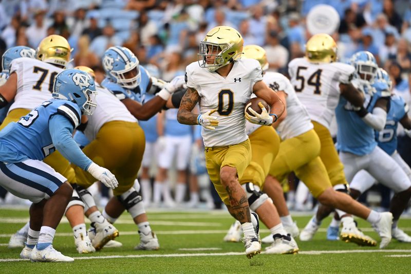 Sep 24, 2022; Chapel Hill, North Carolina, USA; Notre Dame Fighting Irish wide receiver Braden Lenzy (0) with the ball as North Carolina Tar Heels defensive lineman Kaimon Rucker (25) defends in the third quarter at Kenan Memorial Stadium. Mandatory Credit: Bob Donnan-USA TODAY Sports