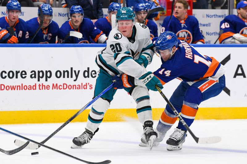 Dec 5, 2023; Elmont, New York, USA; San Jose Sharks left wing Fabian Zetterlund (20) and New York Islanders center Bo Horvat (14) battle for the puck during the third period at UBS Arena. Mandatory Credit: Dennis Schneidler-USA TODAY Sports