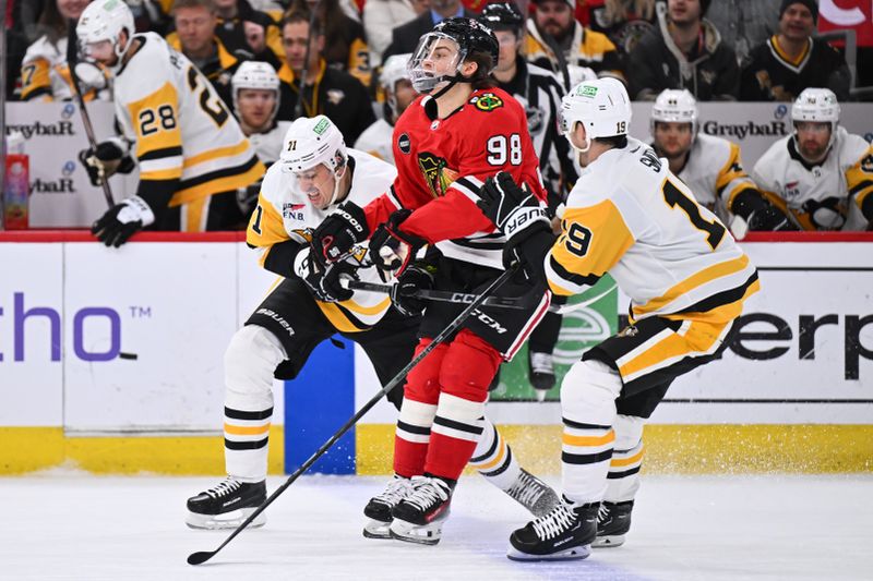 Feb 15, 2024; Chicago, Illinois, USA; Chicago Blackhawks forward Connor Bedard (98) is held up at the blue line by forward Evgeni Malkin (71) and forward Reilly Smith (19) after dumping the puck in the third period at United Center. Mandatory Credit: Jamie Sabau-USA TODAY Sports