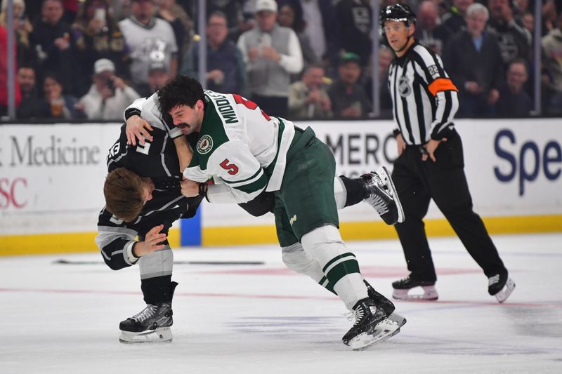 Mar 20, 2024; Los Angeles, California, USA; Los Angeles Kings defenseman Andreas Englund (5) fights Minnesota Wild defenseman Jake Middleton (5) during the first period at Crypto.com Arena. Mandatory Credit: Gary A. Vasquez-USA TODAY Sports