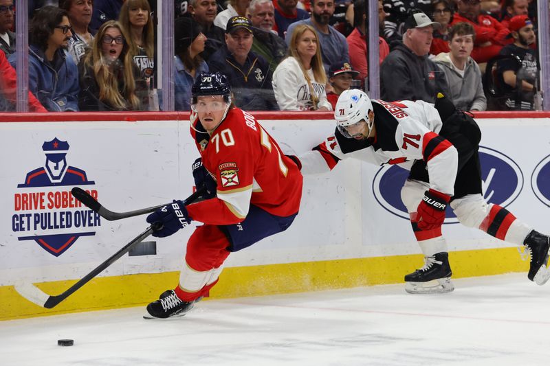 Nov 14, 2024; Sunrise, Florida, USA; Florida Panthers center Jesper Boqvist (70) moves the puck past New Jersey Devils defenseman Jonas Siegenthaler (71) during the second period at Amerant Bank Arena. Mandatory Credit: Sam Navarro-Imagn Images