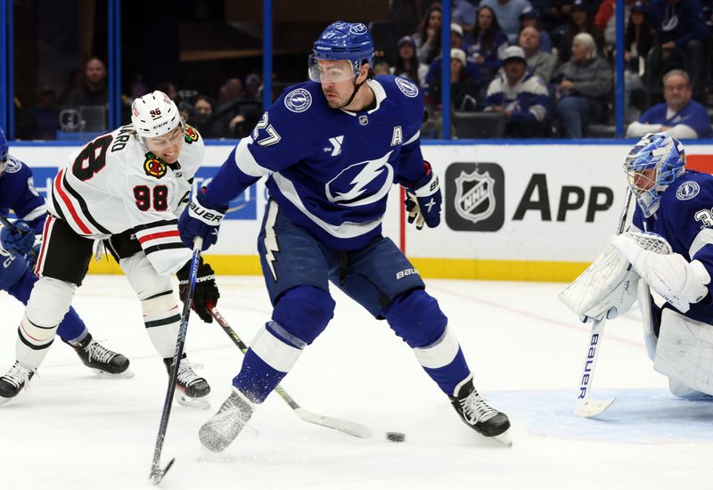 Jan 28, 2025; Tampa, Florida, USA; Chicago Blackhawks center Connor Bedard (98) shoots asTampa Bay Lightning defenseman Ryan McDonagh (27) defends during the second period at Amalie Arena. Mandatory Credit: Kim Klement Neitzel-Imagn Images