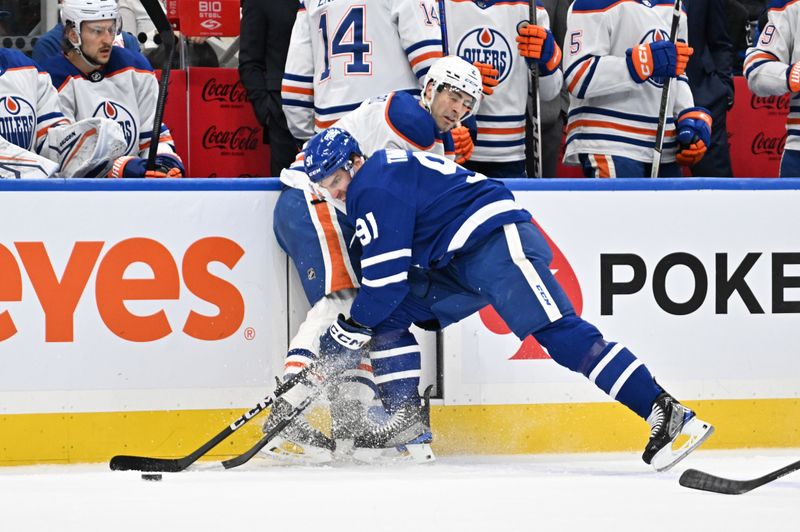 Mar 23, 2024; Toronto, Ontario, CAN; Toronto Maple Leafs forward John Tavares (91) reaches for the puck as Edmonton Oilers defenseman Evan Bouchard (2) defends in the first period at Scotiabank Arena. Mandatory Credit: Dan Hamilton-USA TODAY Sports