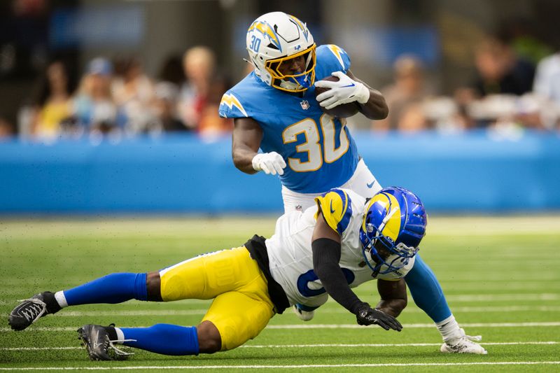 Los Angeles Rams defensive back Tre Tomlinson, bottom, tackles Los Angeles Chargers running back Kimani Vidal during an NFL preseason football game, Saturday, Aug. 17, 2024, in Inglewood, Calif. (AP Photo/Kyusung Gong)