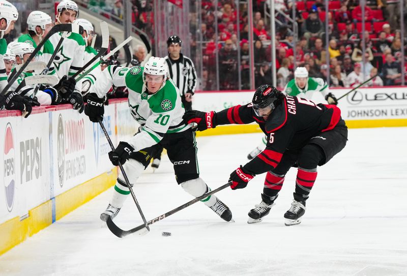 Nov 25, 2024; Raleigh, North Carolina, USA;  Dallas Stars center Oskar Bäck (10) skates with the puck against Carolina Hurricanes defenseman Jalen Chatfield (5) during the second period at Lenovo Center. Mandatory Credit: James Guillory-Imagn Images