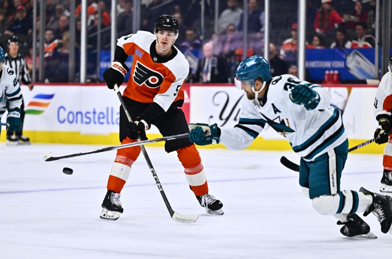 Mar 12, 2024; Philadelphia, Pennsylvania, USA; Philadelphia Flyers defenseman Egor Zamula (5) passes the puck across San Jose Sharks defenseman Mario Ferraro (38) in the third period at Wells Fargo Center. Mandatory Credit: Kyle Ross-USA TODAY Sports