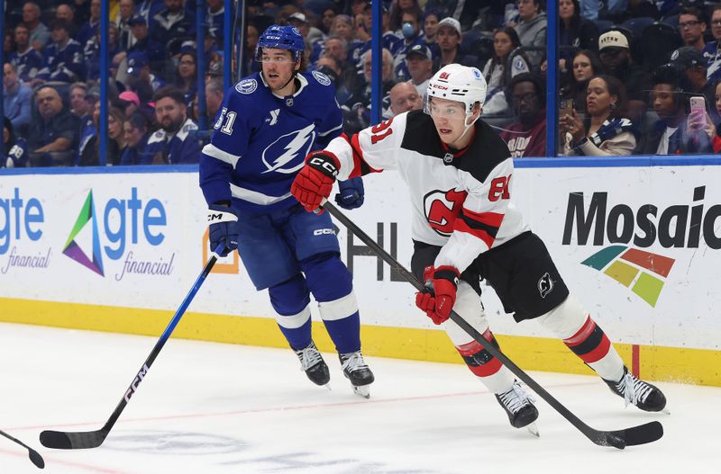 Nov 18, 2025; Tampa, Florida, USA; New Jersey Devils right wing Arseny Gritsyuk (81) skates with the puck as Tampa Bay Lightning defenseman Charle-Edouard D'Astous (51) defends during the second period at Benchmark International Arena. Mandatory Credit: Kim Klement Neitzel-Imagn Images