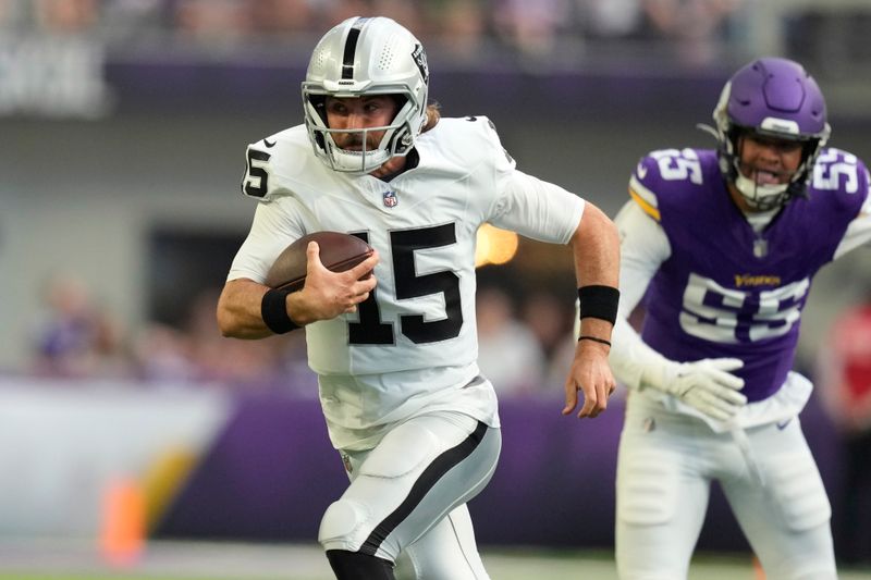 Las Vegas Raiders quarterback Gardner Minshew II (15) scramble past Minnesota Vikings linebacker Andre Carter II (55) during the first half of an NFL football game Saturday, Aug. 10, 2024, in Minneapolis. (AP Photo/Charlie Neibergall)