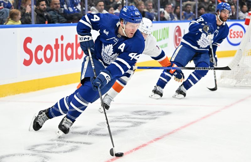 Feb 5, 2024; Toronto, Ontario, CAN;  Toronto Maple Leafs defenseman Morgan Rielly (44) skates with the puck past New York Islanders forward Bo Horvat (14) in the second period at Scotiabank Arena. Mandatory Credit: Dan Hamilton-USA TODAY Sports