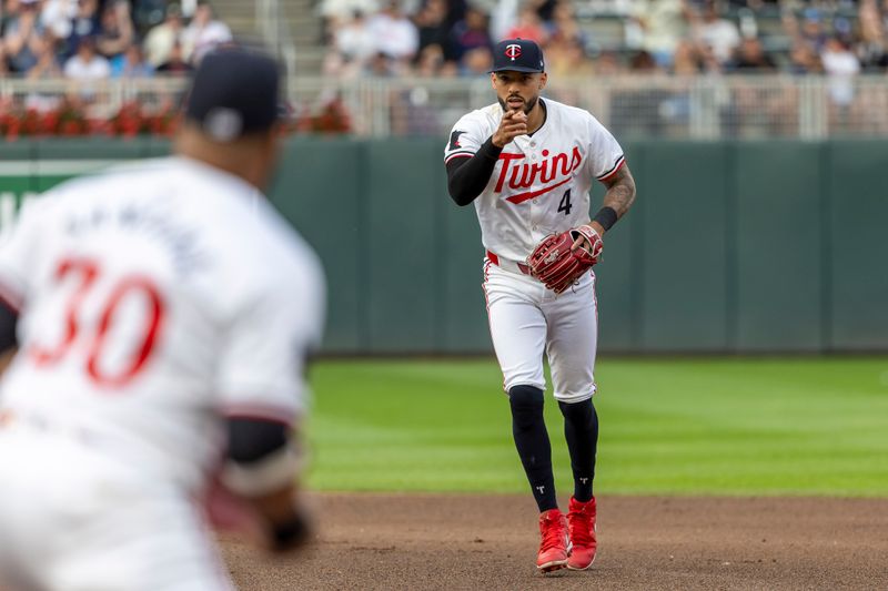 Jun 19, 2024; Minneapolis, Minnesota, USA; Minnesota Twins shortstop Carlos Correa (4) points to Minnesota Twins first baseman Carlos Santana (30) after throwing the ball to first base for a double play agains the Tampa Bay Rays in the fourth inning at Target Field. Mandatory Credit: Jesse Johnson-USA TODAY Sports