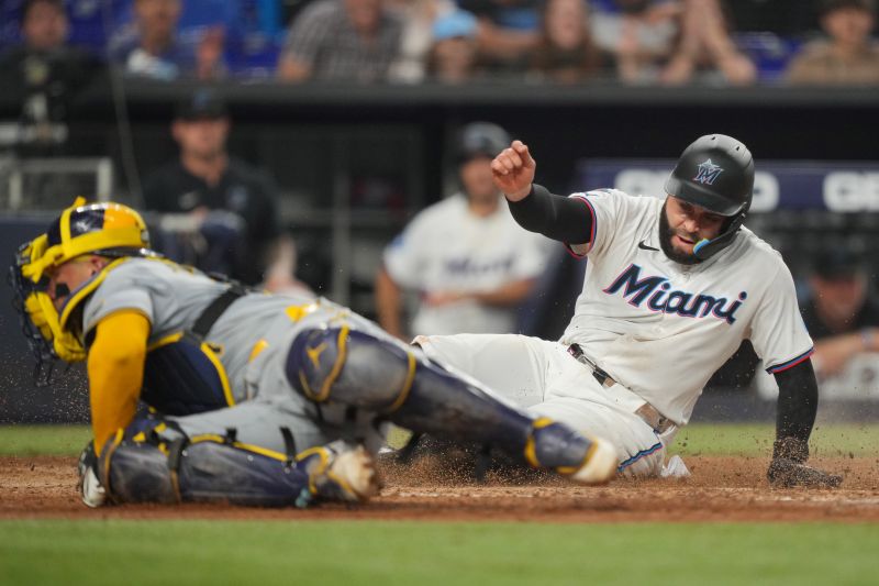 May 21, 2024; Miami, Florida, USA; Miami Marlins third baseman Emmanuel Rivera (15) slides under the tag of Milwaukee Brewers catcher William Contreras (24) to score a run in the sixth inning at loanDepot Park. Mandatory Credit: Jim Rassol-USA TODAY Sports