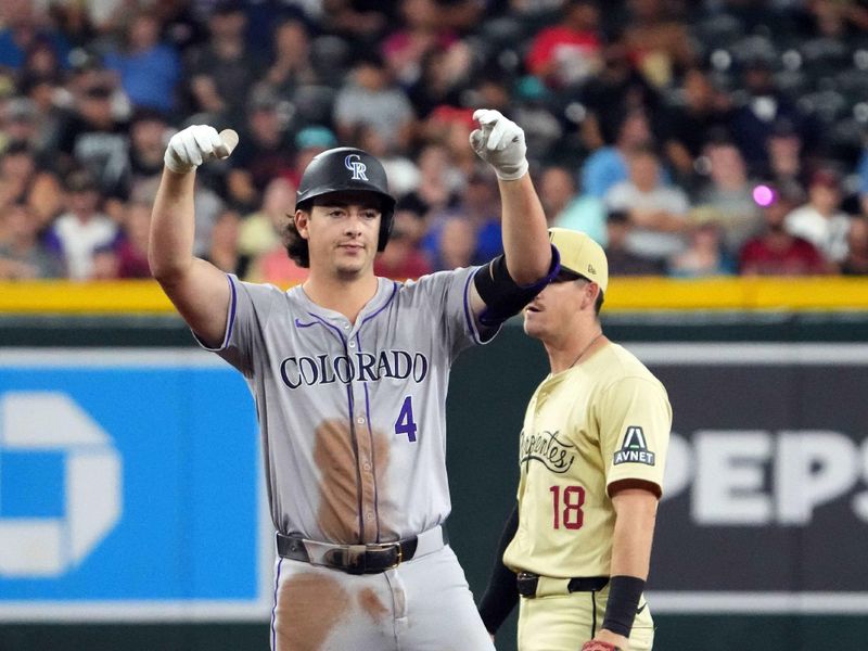 Aug 13, 2024; Phoenix, Arizona, USA; Colorado Rockies first base Michael Toglia (4) celebrates in front of Arizona Diamondbacks shortstop Kevin Newman (18) after hitting an RBI double against the Arizona Diamondbacks during the third inning at Chase Field. Mandatory Credit: Joe Camporeale-USA TODAY Sports