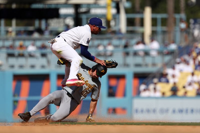 Aug 11, 2024; Los Angeles, California, USA;  Los Angeles Dodgers shortstop Miguel Rojas (11) jumps over Pittsburgh Pirates left fielder Bryan Reynolds (10) to complete a double play during the tenth inning at Dodger Stadium. Mandatory Credit: Kiyoshi Mio-USA TODAY Sports