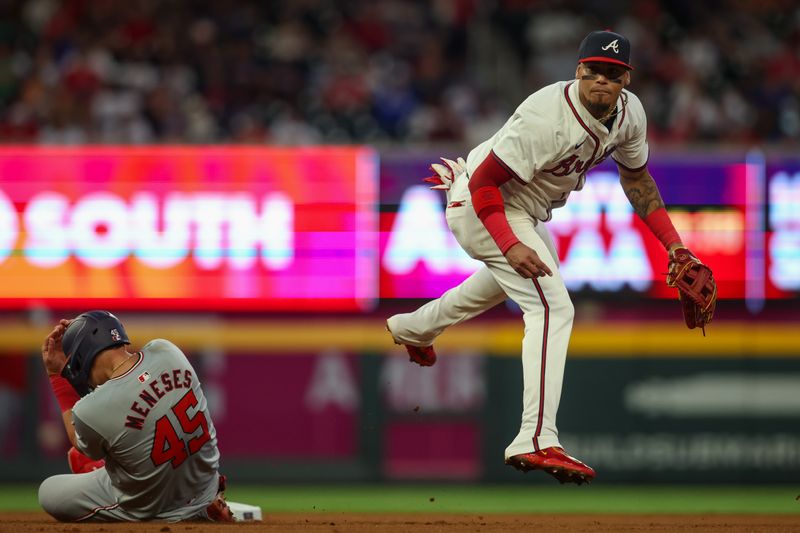 May 28, 2024; Atlanta, Georgia, USA; Atlanta Braves shortstop Orlando Arcia (11) turns a double play over Washington Nationals first baseman Joey Meneses (45) in the seventh inning at Truist Park. Mandatory Credit: Brett Davis-USA TODAY Sports
