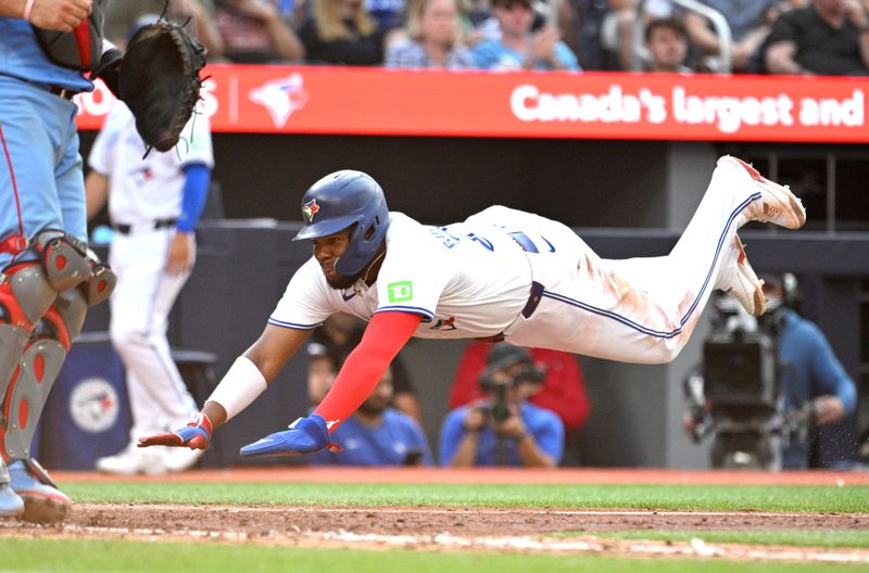 Sep 14, 2024; Toronto, Ontario, CAN;  Toronto Blue Jays first baseman Vladimir Guerrero Jr. (27) dives into home plate to score a run against the St. Louis Cardinals in the seventh inning at Rogers Centre.  Mandatory Credit: Dan Hamilton-Imagn Images