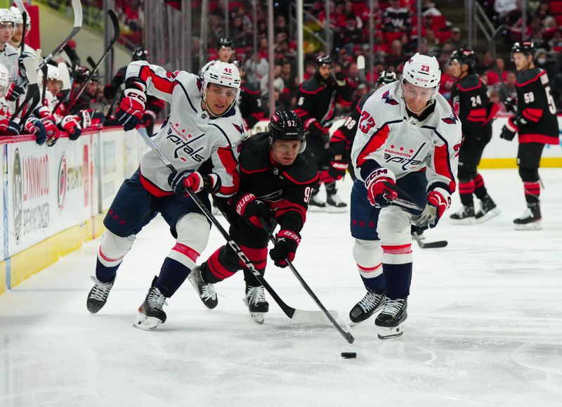 Apr 5, 2024; Raleigh, North Carolina, USA; Washington Capitals defenseman Martin Fehervary (42) and center Michael Sgarbossa (23) battle over the puck against Carolina Hurricanes center Evgeny Kuznetsov (92) during the first period t PNC Arena. Mandatory Credit: James Guillory-USA TODAY Sports