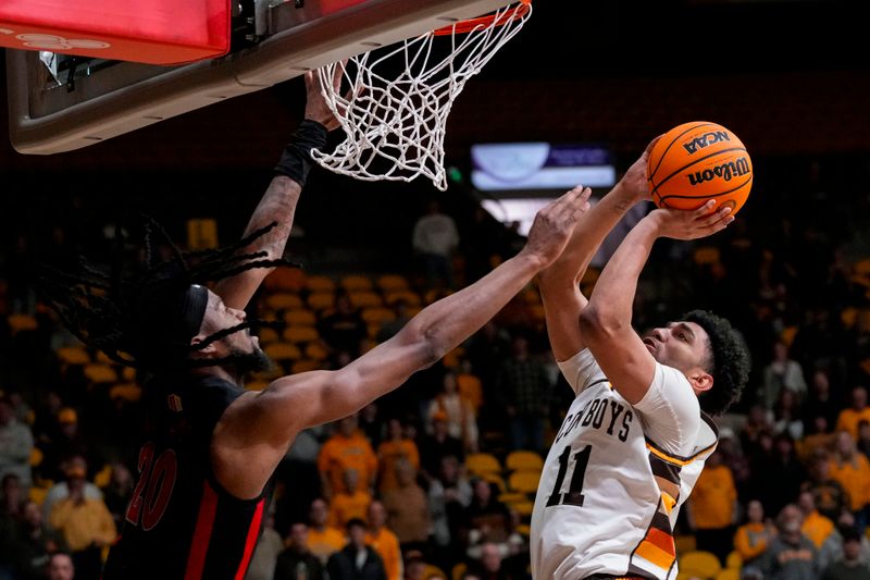 Feb 27, 2024; Laramie, Wyoming, USA; Wyoming Cowboys guard Kael Combs (11) shoots against UNLV Runnin' Rebels forward Keylan Boone (20) during the second half at Arena-Auditorium. Mandatory Credit: Troy Babbitt-USA TODAY Sports