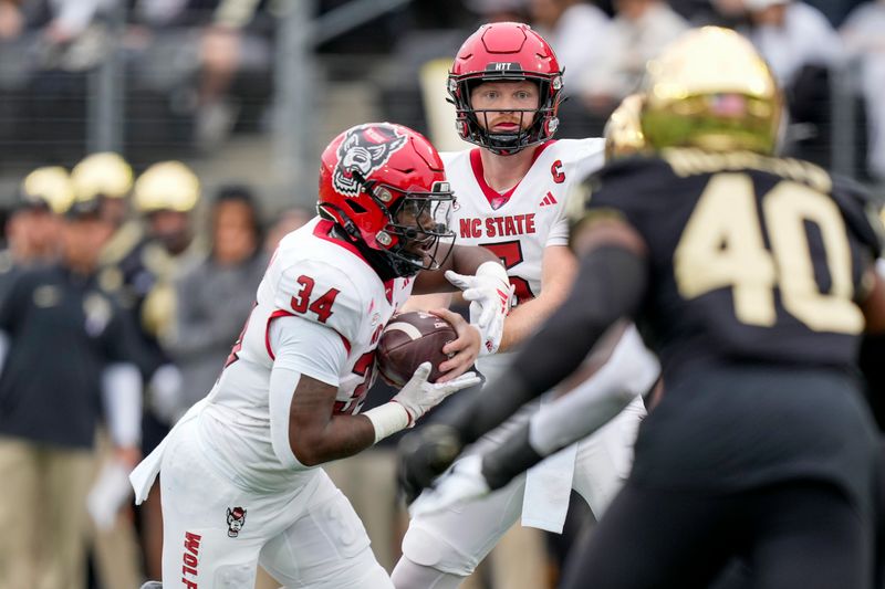 Nov 11, 2023; Winston-Salem, North Carolina, USA; North Carolina State Wolfpack quarterback Brennan Armstrong (5) hands off the ball to running back Delbert Mimms III (34) during the first half at Allegacy Federal Credit Union Stadium. Mandatory Credit: Jim Dedmon-USA TODAY Sports