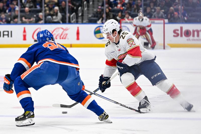 Jan 27, 2024; Elmont, New York, USA; Florida Panthers right wing Mackie Samoskevich (25) skates the puck across the blue line defended by New York Islanders defenseman Sebastian Aho (25) during the first period at UBS Arena. Mandatory Credit: Dennis Schneidler-USA TODAY Sports