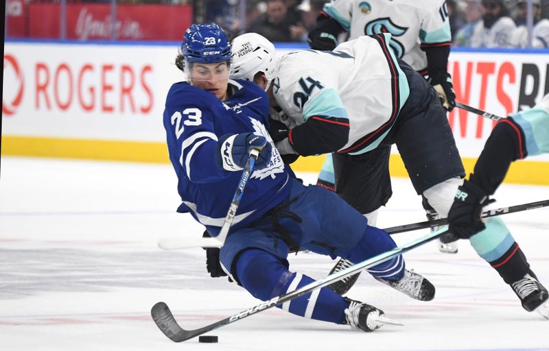 Oct 31, 2024; Toronto, Ontario, CAN;  Toronto Maple Leafs forward Matthew Knies (23) is bodychecked by Seattle Kraken defenseman Jamie Oleksiak (24) in the first period at Scotiabank Arena. Mandatory Credit: Dan Hamilton-Imagn Images