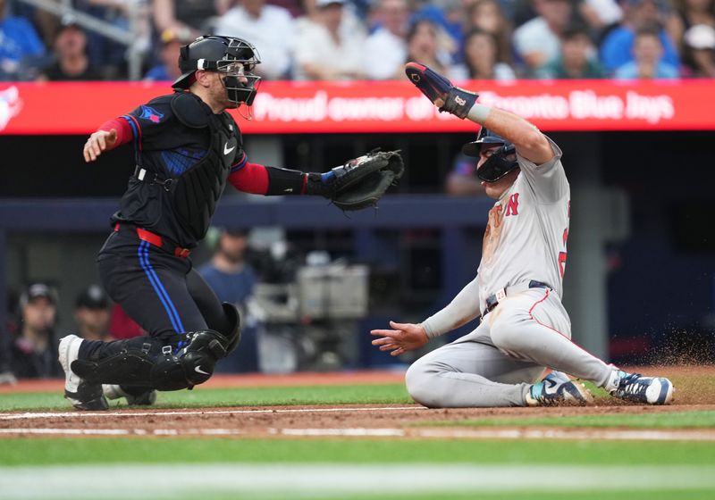 Jun 19, 2024; Toronto, Ontario, CAN; Boston Red Sox center fielder Romy Gonzalez (23) slides into home plate ahead of the tag from Toronto Blue Jays catcher Danny Jansen (9) during the third inning at Rogers Centre. Mandatory Credit: Nick Turchiaro-USA TODAY Sports