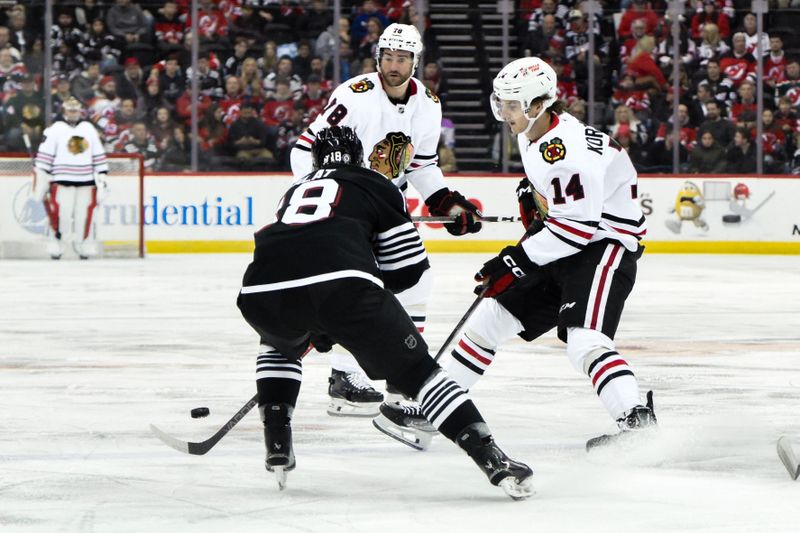 Dec 14, 2024; Newark, New Jersey, USA; Chicago Blackhawks defenseman Kevin Korchinski (14) skates with the puck while being defended by New Jersey Devils left wing Ondrej Palat (18) during the first period at Prudential Center. Mandatory Credit: John Jones-Imagn Images