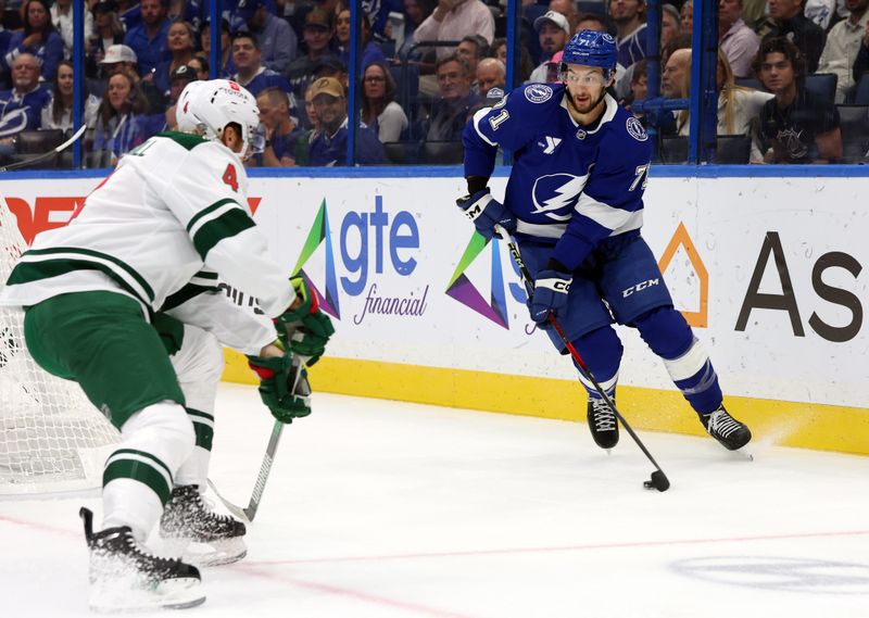 Oct 24, 2024; Tampa, Florida, USA; Tampa Bay Lightning center Anthony Cirelli (71) skates with the puck as Minnesota Wild defenseman Jon Merrill (4) defends during the first period at Amalie Arena. Mandatory Credit: Kim Klement Neitzel-Imagn Images