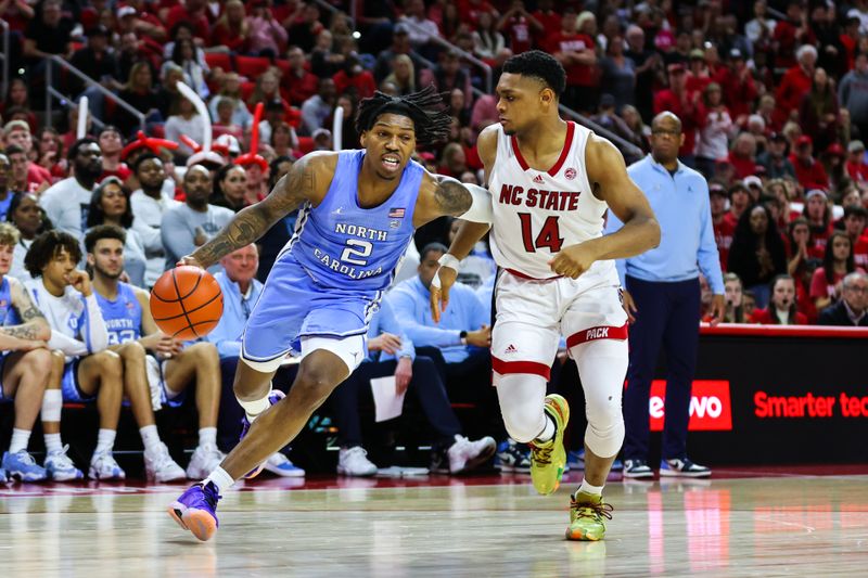 Feb 19, 2023; Raleigh, North Carolina, USA;  North Carolina Tar Heels guard Caleb Love (2) dribbles against North Carolina State Wolfpack guard Casey Morsell (14) during the second half of the game at PNC Arena. Mandatory Credit: Jaylynn Nash-USA TODAY Sports