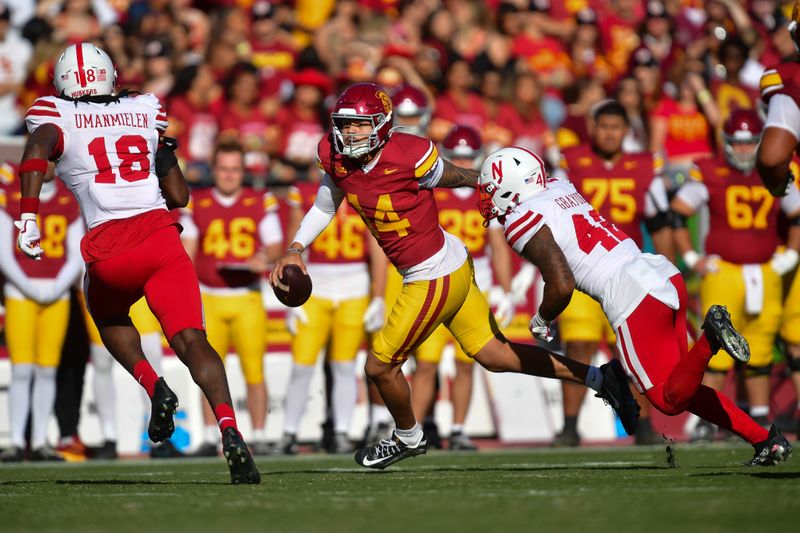 Nov 16, 2024; Los Angeles, California, USA; Southern California Trojans quarterback Jayden Maiava (14) runs the ball against Nebraska Cornhuskers linebacker Princewill Umanmielen (18) and linebacker Mikai Gbayor (42) during the first half at the Los Angeles Memorial Coliseum. Mandatory Credit: Gary A. Vasquez-Imagn Images