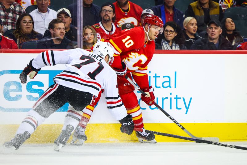 Oct 15, 2024; Calgary, Alberta, CAN; Calgary Flames center Jonathan Huberdeau (10) and Chicago Blackhawks left wing Taylor Hall (71) battles for the puck during the second period at Scotiabank Saddledome. Mandatory Credit: Sergei Belski-Imagn Images