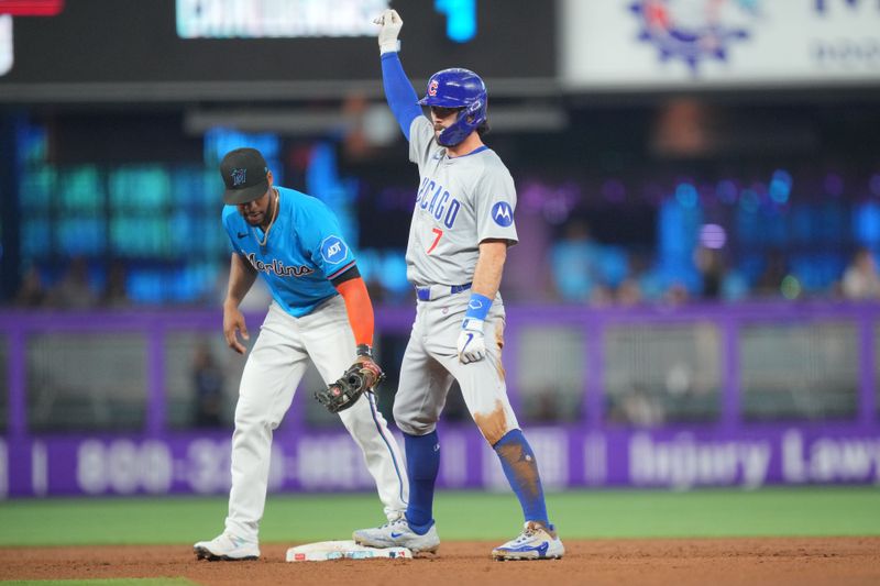 Aug 25, 2024; Miami, Florida, USA;  Chicago Cubs shortstop Dansby Swanson (7) celebrates a double in the second inning as Miami Marlins shortstop Vidal Bruján (17) applies the tag at loanDepot Park. Mandatory Credit: Jim Rassol-USA TODAY Sports