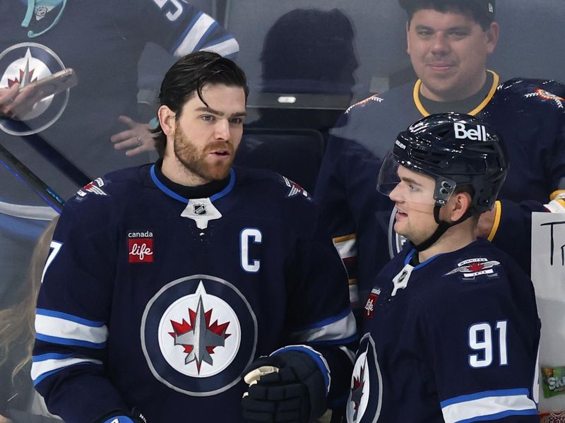 Dec 14, 2024; Winnipeg, Manitoba, CAN; Winnipeg Jets center Adam Lowry (17) and Winnipeg Jets center Cole Perfetti (91) talk before a game against the Montreal Canadiens at Canada Life Centre. Mandatory Credit: James Carey Lauder-Imagn Images