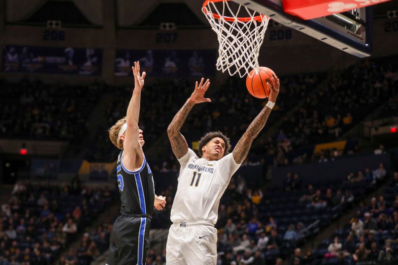 Feb 11, 2025; Morgantown, West Virginia, USA; West Virginia Mountaineers guard Jonathan Powell (11) shoots against Brigham Young Cougars forward Richie Saunders (15) during the first half at WVU Coliseum. Mandatory Credit: Ben Queen-Imagn Images