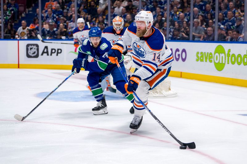 May 10, 2024; Vancouver, British Columbia, CAN; Vancouver Canucks forward Pius Suter (24) watches Edmonton Oilers defenseman Mattias Ekholm (14) handle the puck during the third period in game two of the second round of the 2024 Stanley Cup Playoffs at Rogers Arena. Mandatory Credit: Bob Frid-USA TODAY Sports